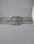A close-up of a mannequin wearing SUZI ROHER’s 6826 decorative silver chain belt with a large oval buckle, displayed over form-fitting gray fabric.