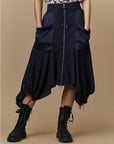 Someone wears the HIGH Uphold navy blue tech satin cargo-inspired skirt with large front pockets, an elasticated waistband, center zipper, and drawstring hems, paired with black lace-up combat boots against a plain beige background.