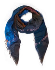 The Clarity scarf by SUZI ROHER is a square, Italian-made modal silk accessory featuring blue, brown, and black hues, frayed edges, and uplifting words like EXCEL and FUTURE printed in light tones.