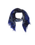 The Lily, Style Icon scarf by SUZI ROHER, featuring blue and gray tones with circular patterns and frayed edges, is displayed on a white background—an ideal accessory to channel a tomboy vibe when paired with classic trousers in iconic Katharine Hepburn style.