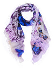 The SUZI ROHER Social Butterfly scarf features blue and purple butterfly prints on light purple fabric with fringed edges, displayed in a loose loop against a white background.