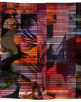 A woven textile from SUZI ROHER, called “Lily, True to Form,” features overlapping abstract shapes, human faces, and animals in warm tones. Vertical and horizontal lines create a plaid effect across the design, and the piece is finished with fringed edges.