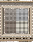 The Sechura Desert by SUZI ROHER is a square woven textile with intricate black, white, and beige geometric patterns. A dense central grid fades from dark to light and is beautifully bordered with decorative fringes along the edges.