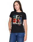 Woman with long brown hair wears The Niki by SUZI ROHER, a black 100% cotton crew neck tee with a colorful collage graphic, styled with blue jeans and a bracelet, posing with one hand in her pocket against a white background.