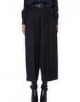 A person wears the High Sleek high-waisted wide-leg pants, styled with a black belt, black heeled ankle boots, and a dark long-sleeve top. The outfit is shown from shoulders to feet against a white background.