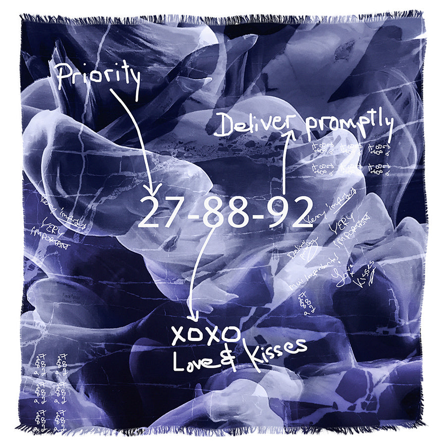 The SUZI ROHER "27-88-92" scarf features a blue and purple abstract design with handwritten phrases like “Priority,” “Deliver promptly,” and code numbers, evoking communication shorthand over a textured background.