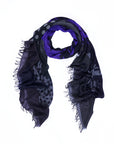 Here’s the rewritten sentence using your product data: The “Lucy” scarf by SUZI ROHER is displayed in a loose circular shape on a white background, showcasing its black and purple hues with fringed edges, adorned with polka dot and abstract patterns inspired by original digitally printed art.