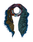 The SUZI ROHER “Honor” scarf is a multicolored accessory with frayed edges, showcasing abstract patterns and understated Japanese artwork and text on a vibrant backdrop of teal, blue, brown, and purple tones. It is presented against a white background.