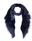 A SUZI ROHER Elizabeth B&W scarf, featuring digitally printed original artwork in dark blue and black with frayed edges, is arranged in a loose loop on a white background.