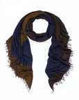 The SUZI ROHER Elizabeth Brown scarf is loosely folded and shown on a white background, featuring original artwork digitally printed in dark blue and brown tones with frayed edges for a unique and timeless look.