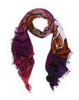 The SUZI ROHER “Scarlett” scarf, lightweight and multicolored with frayed edges, is loosely arranged in a loop against a white background. Featuring abstract patterns in shades of purple, red, orange, and black accented by handwritten text, its vibrant design is inspired by original artwork and digitally printed for exceptional detail.