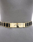 A close-up of the SUZI ROHER Brandy belt, featuring gold rectangular frames with black textured insets and a metallic clasp, styled on a gray dress form.