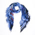 The SUZI ROHER "Love Of Music" scarf features blue, black, white, and red patterns with frayed edges, presented in a loose circular shape on a white background, capturing musical joy and vibrant color.