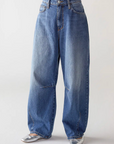 A person wears SHAFT Barrel Patriot Jeans—high-waisted, wide-leg blue denim with a relaxed fit and classic five-pocket style—paired with silver pointed-toe shoes against a plain light background.