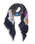 The "50 Shades of Gray" scarf by SUZI ROHER features abstract patterns and geometric designs on a white base, with frayed edges, colorful dots, and printed text—creating a unique, expressive accessory that resembles wearable art.