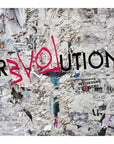 A wall layered with torn paper ads shows “REVOLUTION” in bold black, with “EVOL” in pink—evoking urban chaos. Ideal for fans of SUZI ROHER’s Love Revolution archival or giclee prints.