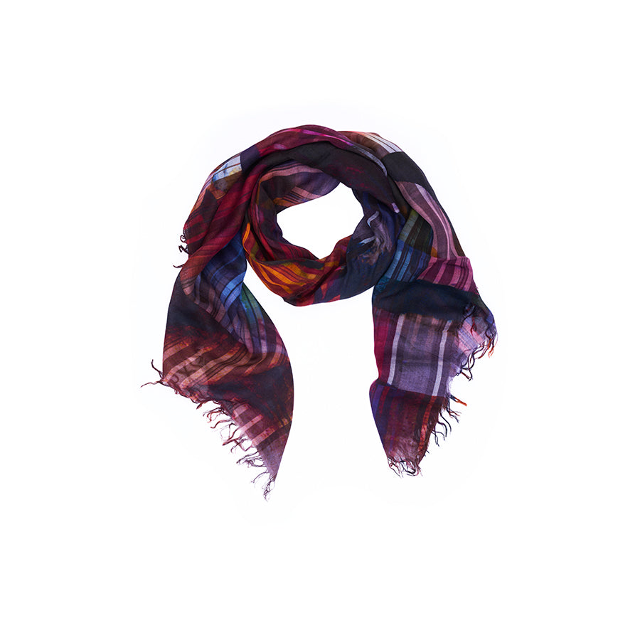 The “Lily, Tutti Matti” scarf by SUZI ROHER, displayed in a loose loop on a white background, showcases original Venice postcard-inspired artwork in vibrant plaid patterns with fringed edges and a digital print finish.