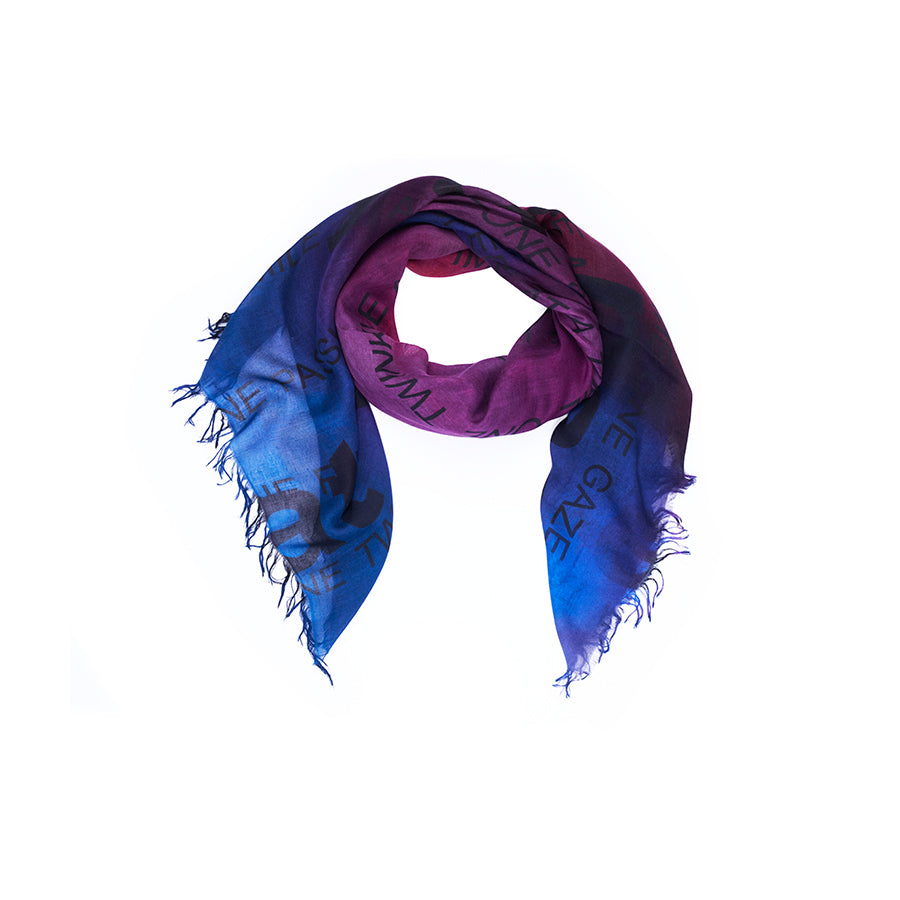 The “Lily, Your Own Pace” scarf by SUZI ROHER features a blue and purple gradient with black printed text, finished with fringed edges. Arranged in a circular shape against a white background, this Italian-made piece showcases original artwork digitally printed onto the fabric.