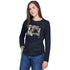 A woman with long brown hair wears SUZI ROHER's "The Catherine," a navy blue long-sleeve shirt with a black-and-white photo collage, styled with blue jeans—an exclusive, sophisticated look against a white background.