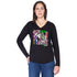 Channeling New York style, a woman with long brown hair wears SUZI ROHER’s "The Victoria"—a black long-sleeve shirt with a vibrant abstract graphic—paired with blue jeans and gold jewelry, posing confidently with one hand on her hip.