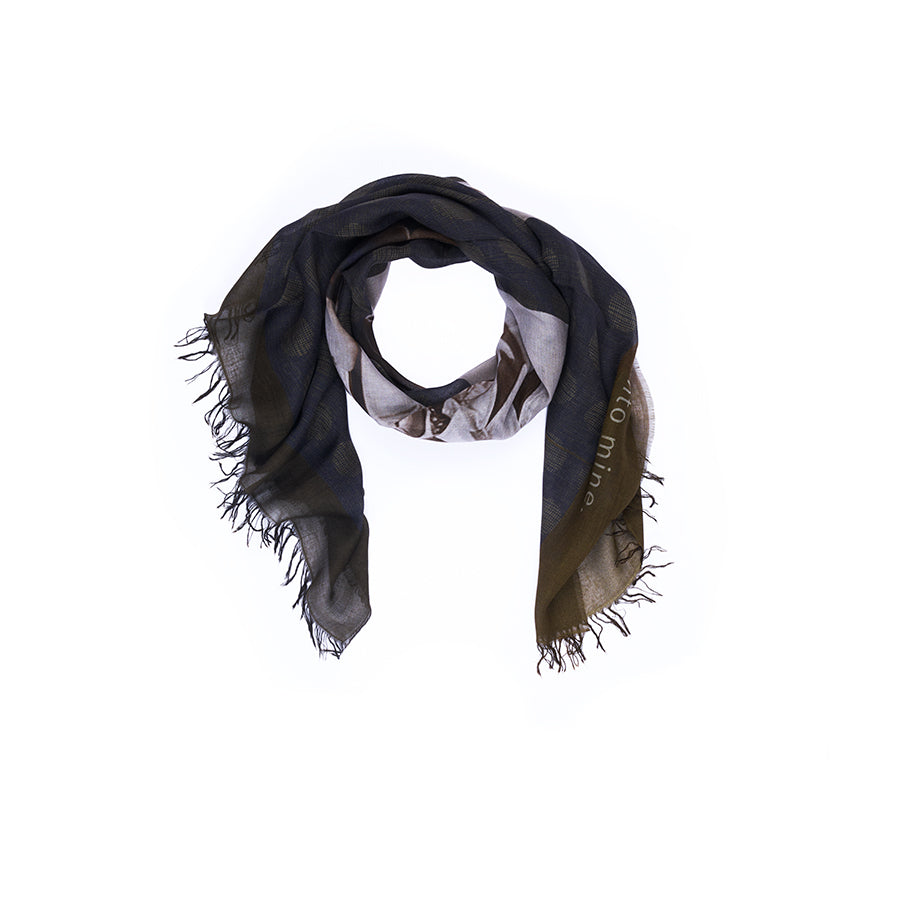 A SUZI ROHER “Lily, Play It Again” scarf in black and beige, featuring digitally printed original artwork and fringed edges, is loosely arranged in a circular shape on a white background.