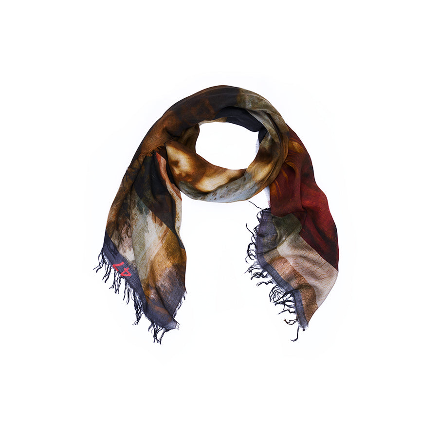A loosely wrapped SUZI ROHER scarf, “Lily, Da Vinci,” with fringe edges in shades of brown, red, and black—Renaissance artwork-inspired and displayed against a plain white background.