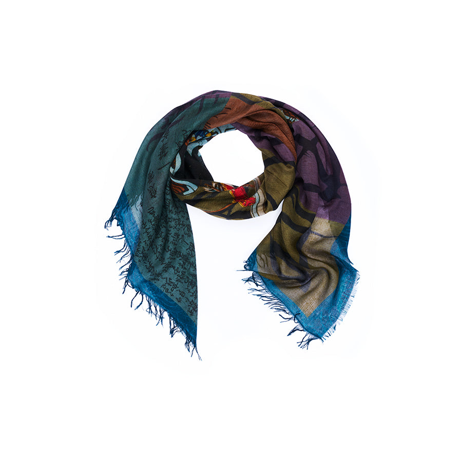 A multicolored “Lily, Honor” scarf by SUZI ROHER, showcasing blue, green, and purple tones with a subtle Japanese print pattern and fringed edges, is elegantly arranged in a loose coil on a white background.