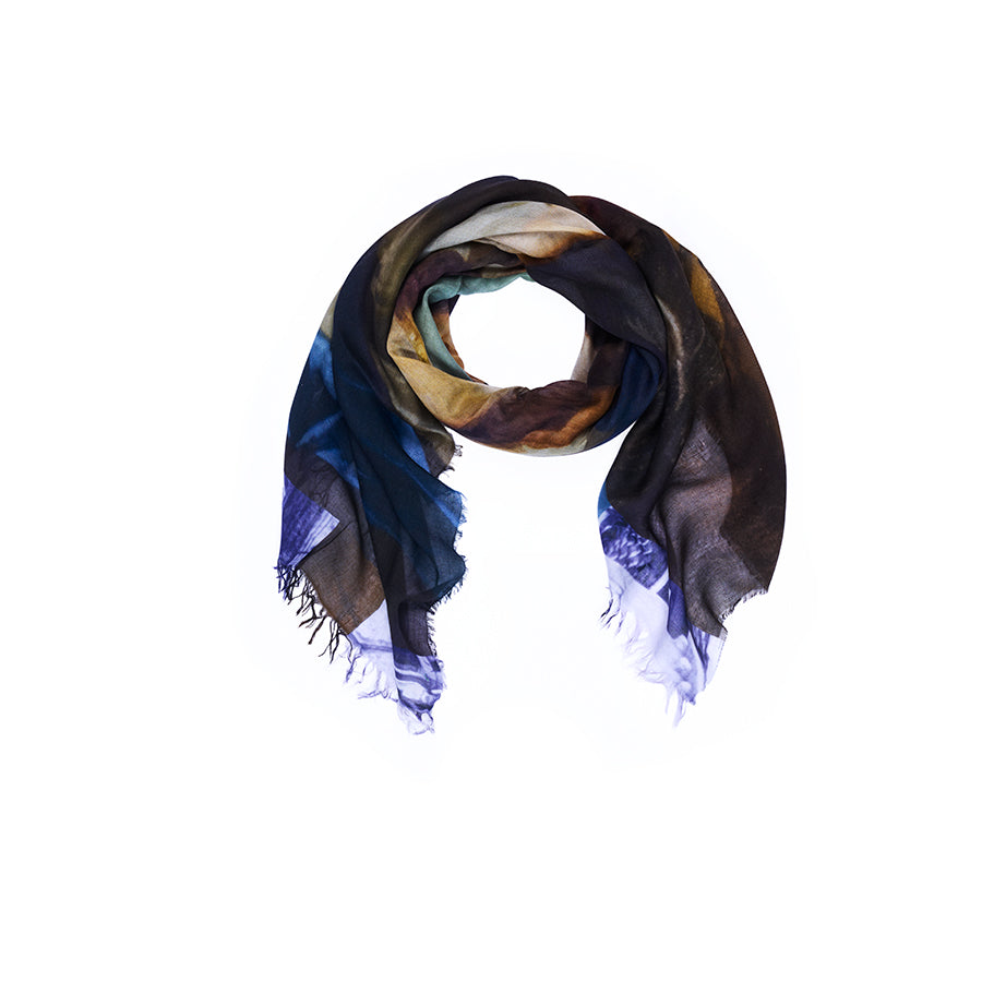 The “Lily, Poetry” scarf by SUZI ROHER is a multicolored, lightweight accessory displayed in a circular arrangement on a white background. Featuring shades of blue, brown, yellow, and touches of green with frayed edges, this scarf showcases original artwork digitally printed for vibrant color and detail. Hand washable for easy care.