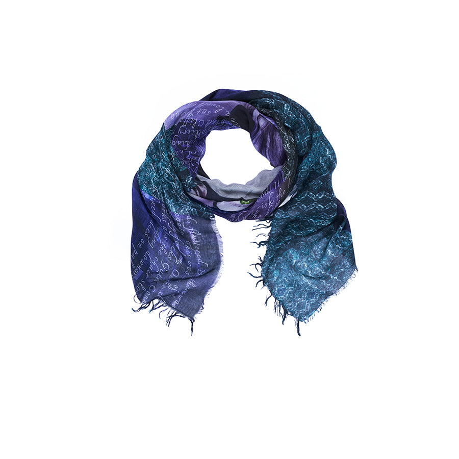 The SUZI ROHER “Lily, Lady Chatterley” scarf, featuring a blue and purple palette with frayed edges and a handwritten script inspired by D. H. Lawrence, is arranged in a circular shape on a white background.