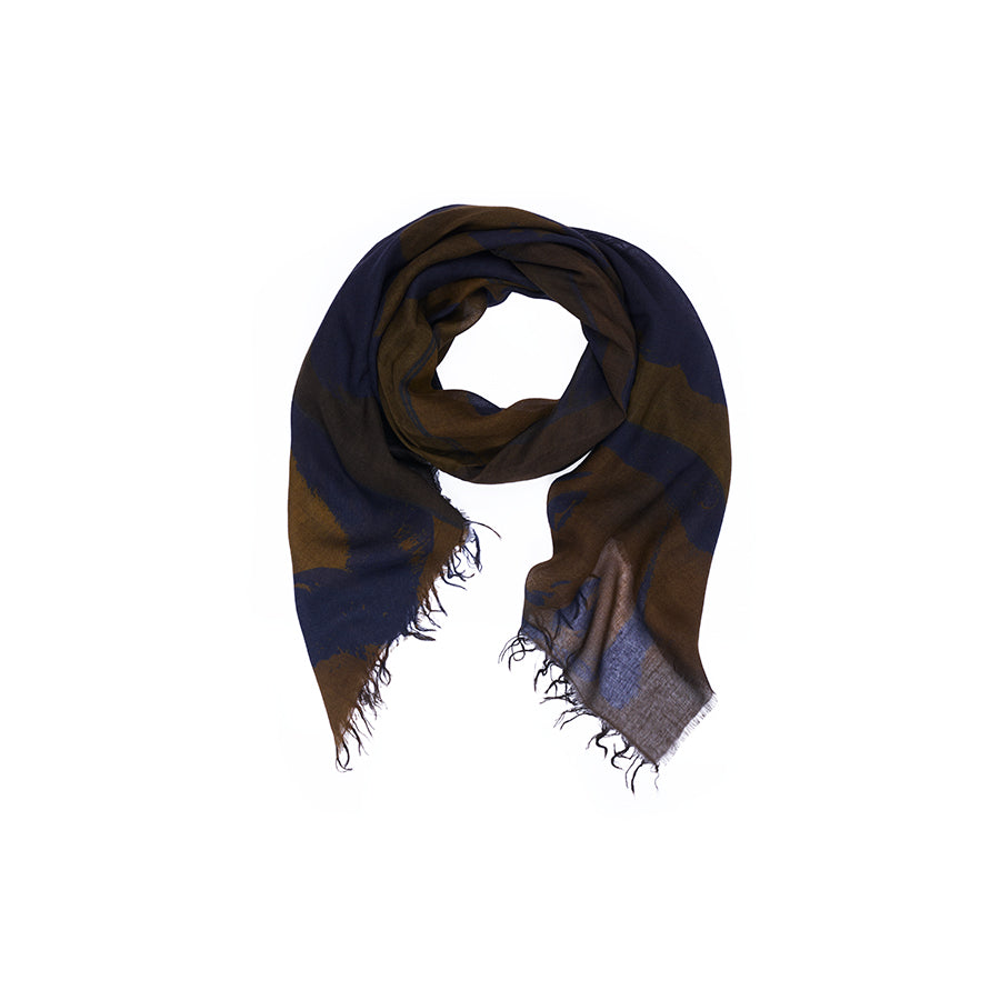 The SUZI ROHER “Lily, Elizabeth Brown” square scarf, showcasing a dark blue and brown striped pattern inspired by original artwork and finished with frayed edges, is neatly folded in a circular shape on a white background.