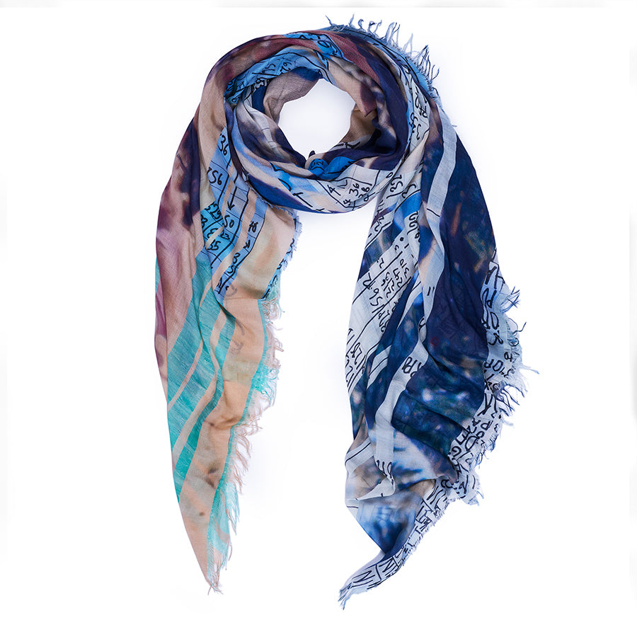 Multicoloured scarf with artwork of a day at the beach, in sky blues to sea green, with the sandy colour in between.