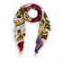 The SUZI ROHER "Le Jardin" scarf is a lightweight accessory featuring frayed edges and a vibrant floral print in red, yellow, green, and purple on white, elegantly draped in a loose loop against a plain white background.
