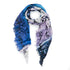 The SUZI ROHER "Love Note" scarf is lightweight, with a blue, purple, and white gradient, black abstract letter design like a love note, and frayed edges—styled in a loose loop.