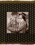 “Play It Again” by SUZI ROHER features a striking black and white image of a man and woman in trench coats and hats tenderly embracing, their eyes locked in a cinematic moment. The scene is framed by film quotes on a rich brown patterned background, capturing the timeless allure of classic movies.