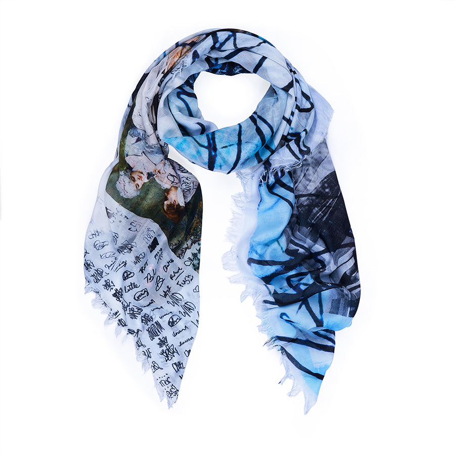 The SUZI ROHER "To Enjoy" scarf is lightweight with frayed edges, featuring abstract blue and black lines, handwritten-style text, and a painted section of classical figures—ideal for daily wear or as a gift.