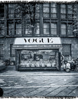 Black-and-white photo titled “Vogue Italia B&W” by SUZI ROHER, featuring a street newsstand with a prominent VOGUE sign, surrounded by parked scooters and motorcycles in front of an old building with tall windows and intricate architectural details.