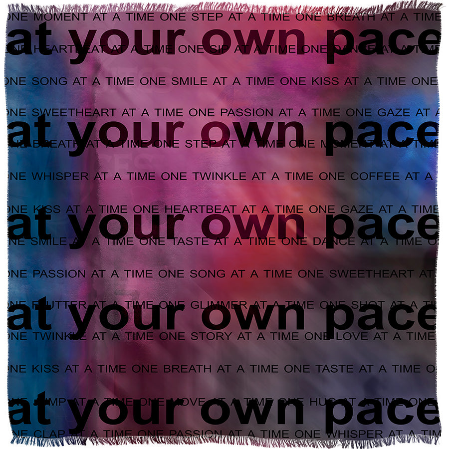 The “Your Own Pace” woven blanket by SUZI ROHER features the phrase “at your own pace” in bold black letters across a vibrant, colorful background adorned with smaller motivational messages.
