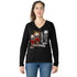 A woman with long brown hair in a ponytail wears SUZI ROHER's The Violet, a 100% cotton black V-neck long-sleeve shirt featuring a graphic of two women using vintage payphones, one in color and one in black and white, against a white background.