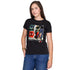 A woman with long brown hair wears The Niki by SUZI ROHER—a black 100% cotton tee with a vibrant DAILY PLANET graphic and crew neck—paired with blue jeans, posing against a white background with one hand in her pocket.