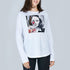 A woman with dark hair smiles in The Catherine by SUZI ROHER—a slim fit, 100% cotton crew neck tee with a black-and-white woman's face, a red heart over one eye, and bold abstract art—standing against a light gray background.