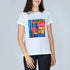 A woman is shown from the torso up, smiling and wearing SUZI ROHER's The Niki t-shirt, which features colorful, upright book spines on the front. The background is plain light gray.