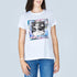 A woman wears The Niki T-shirt by SUZI ROHER, featuring a colorful rectangle graphic with a black-and-white Audrey Hepburn photo and the words "Silver Screen," paired with blue jeans and a slight smile.